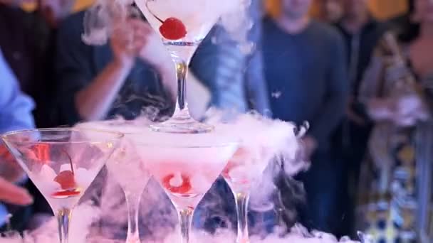パーティーでのスモーキーカクテル。たくさんのお酒と桜が煙を出しています。ナイトクラブで創造的なカクテルアプローチ。パーティーでシャンパンのピラミッド。スローモーション — ストック動画