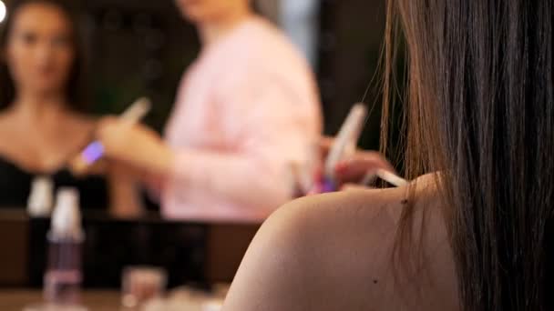 Artista de maquillaje hace maquillaje corporal usando polvo. Joven hermosa chica con el pelo largo hace maquillaje en un salón de belleza — Vídeos de Stock