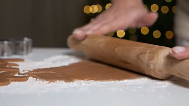 Fazendo deliciosos homens de gengibre. Uma jovem rola massa com um rolo para pão de gengibre. As mãos trabalham com o teste. Doces de Natal — Vídeo de Stock