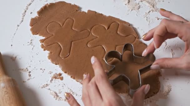 Fazendo biscoitos de gengibre para o Natal em casa. O processo de fazer biscoitos gengibre. As mãos de meninas close-up preparam biscoitos. Dona de casa faz biscoitos de Natal usando várias formas — Vídeo de Stock
