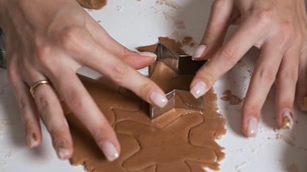 Fazendo biscoitos de gengibre para o Natal em casa. O processo de fazer biscoitos gengibre. As mãos de meninas close-up preparam biscoitos. Dona de casa faz biscoitos de Natal usando várias formas — Vídeo de Stock