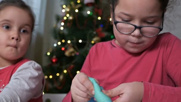 Crianças pequenas decoram biscoitos de gengibre de Natal com creme em um fundo da árvore de Natal.Biscoitos de Natal em casa — Vídeo de Stock