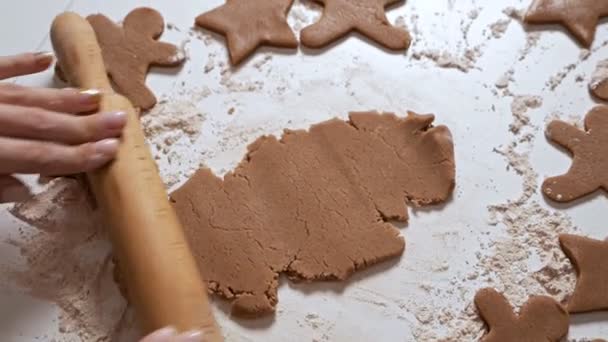 Fazendo deliciosos homens de gengibre. Uma jovem rola massa com um rolo para pão de gengibre. As mãos trabalham com o teste. Doces de Natal — Vídeo de Stock