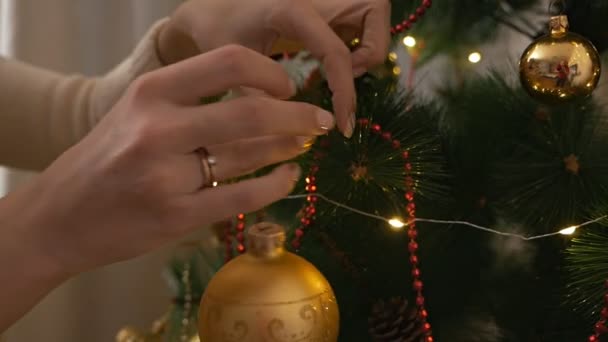 Vrouwelijke handen versieren de kerstboom met mooie glazen ballen — Stockvideo