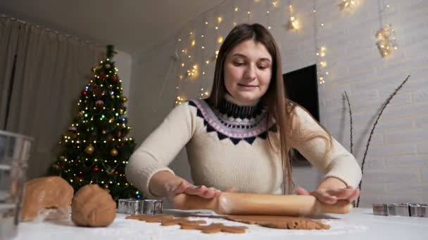 Делать вкусные пряничные человеки.Молодая девушка катит тесто со скалкой для пряничных пряников. Руки работают с тестом. Рождественские сладости — стоковое видео