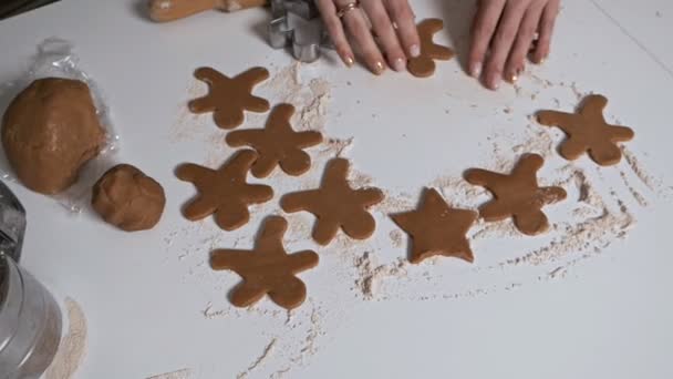 O processo de fazer biscoitos de gengibre na forma de uma árvore de Natal, estrelas, homem, corações de massa crua na mesa. Diversão, feriados, doces — Vídeo de Stock