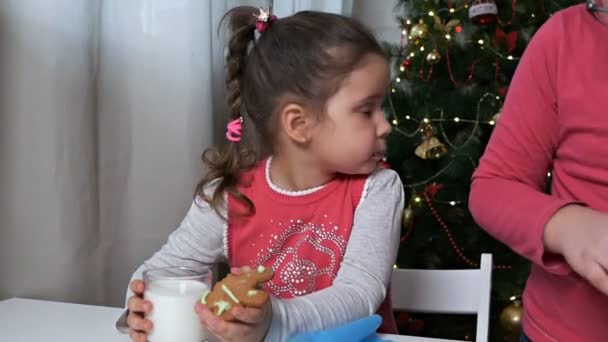 Очаровательный ребенок с пряничным печеньем и стаканом молока. Традиционные рождественские угощения, еда — стоковое видео