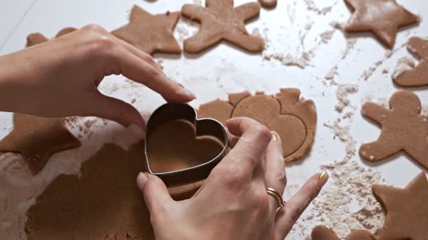 Η νοικοκυρά φτιάχνει χριστουγεννιάτικα μπισκότα. Η γυναίκα έφτιαξε ένα σχήμα μελόψωμου σε μορφή καρδιάς από ακατέργαστη ζύμη — Αρχείο Βίντεο