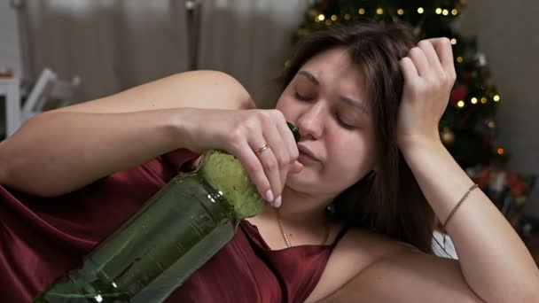 Пьяная женщина пьет стакан воды в постели на фоне рождественской елки после вечеринки, концепция похмелья — стоковое видео