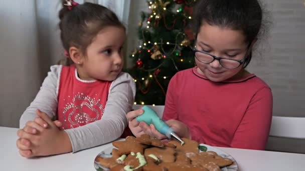 Kids bake christmas cookies at home.The process of decorating Christmas cookies. Children decorate the gingerbread cookies in the form of a Christmas tree and little men