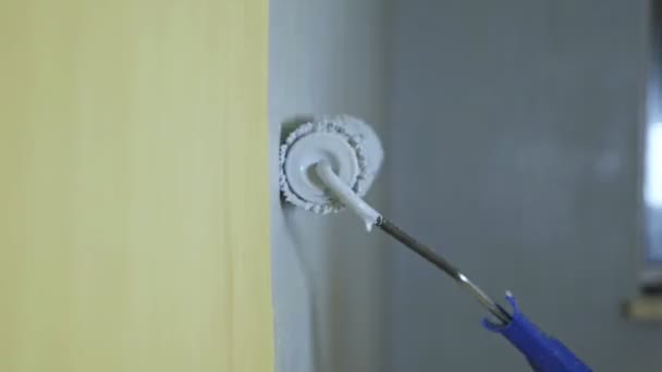 Rodillo de construcción pinta la pared amarilla con pintura gris — Vídeo de stock