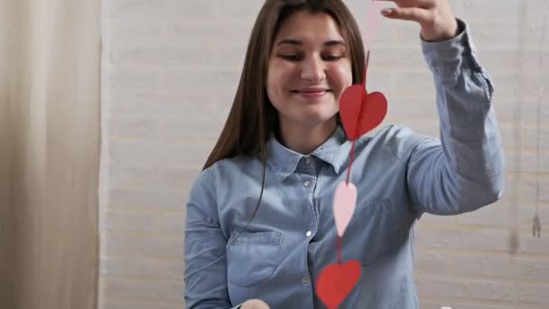 Genç ve çekici bir kız Sevgililer Günü 'nde bir dairede kalp dekorasyonu hazırladı. — Stok video