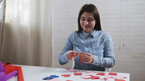 Jong aantrekkelijk meisje bereidt decoraties in een appartement voor Valentijnsdag — Stockvideo