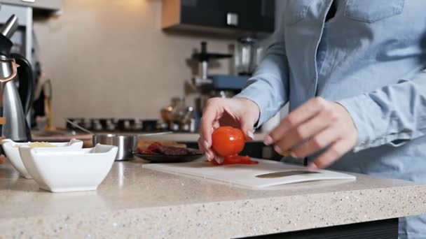 Το κορίτσι κόβει με μαχαίρι μια ώριμη ζουμερή ντομάτα. Τεμαχισμός νωπών λαχανικών για πίτσα — Αρχείο Βίντεο