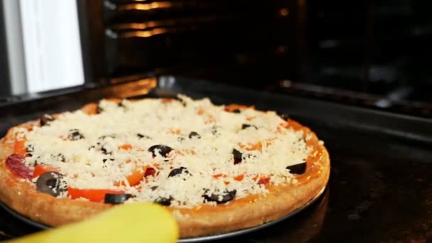 Uma mulher põe pizza no forno. Cozinhar pizza italiana em um forno de convecção elétrica. pizza com queijo mussarela com tomates salame — Vídeo de Stock