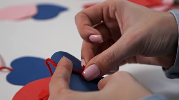 Kreatywność dziewczyny została wycięta z czerwonego papieru nożyczkami, sercami, kwiatami, elementami do kart dla kochanków. Walentynki dekoracji domu — Wideo stockowe