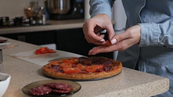 Cooking Italian pizza at home, a girl puts tomatoes on a pizza — Stock Video