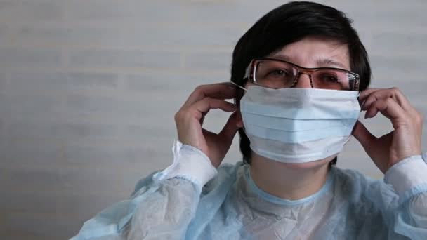 Kvinnlig läkare tar på sig en medicinsk mask för arbete. Begreppet hälso- och sjukvård — Stockvideo