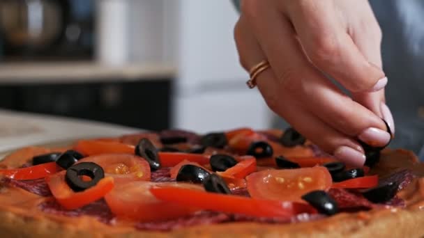 Cocinar pizza italiana en casa, una chica pone aceitunas en la pizza — Vídeo de stock