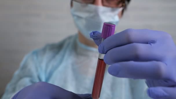 Kadın doktor bir laboratuarda deney yapıyor. Elinde kan testi şişesi var. — Stok video