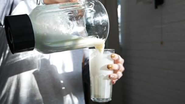 Женщина наливает из блендера, миксера приготовленный витаминный коктейль в стакан — стоковое видео