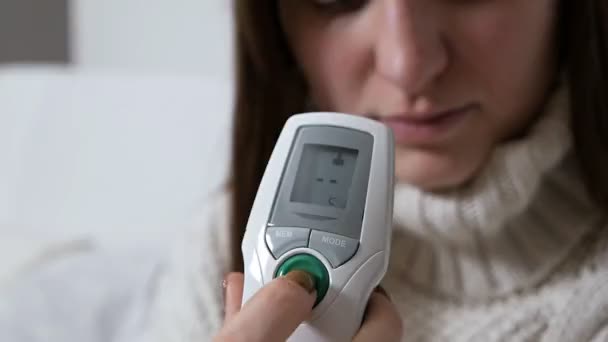 Fille vérifier la température avec un thermomètre infrarouge médical électronique. Concept de santé et de soins médicaux — Video