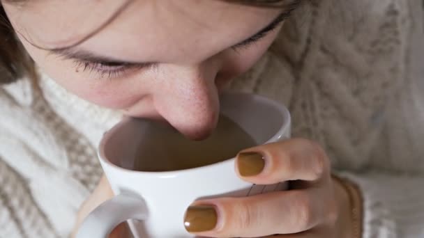 Fille malsaine tenant une tasse de thé chaud. La malheureuse jeune femme malade attrapa un rhume, gela, se soigna seule avec des médicaments à la maison — Video