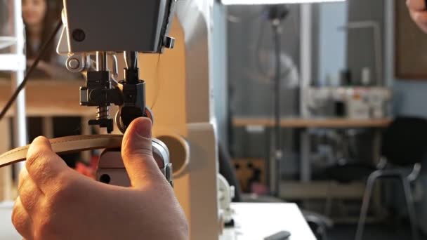 Máquina de coser aguja en movimiento. Un primer plano de la aguja de una máquina de coser se mueve rápidamente hacia arriba y hacia abajo. El sastre cose un cinturón de cuero en un taller de costura. Proceso de costura de cuero — Vídeo de stock