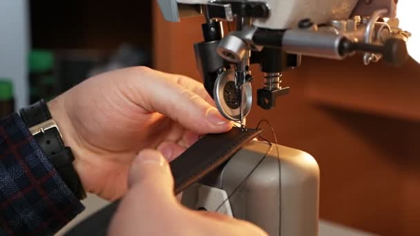 Máquina de coser aguja en movimiento. Un primer plano de la aguja de una máquina de coser se mueve rápidamente hacia arriba y hacia abajo. El sastre cose un cinturón de cuero en un taller de costura. Proceso de costura de cuero — Vídeo de stock