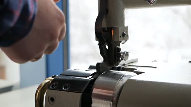 Un tanneur mâle coupe l'excès de peau d'un produit à l'aide d'une équarrisseuse spéciale dans un atelier de production. Machine de découpe de bord de peau — Video