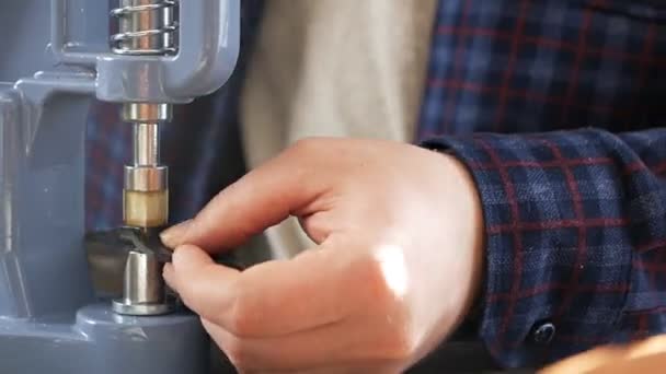 Ein Handwerker verwendet eine Presse, um Metallbeschläge zu montieren. Er fixiert das Teil mit dem Drahtreifer im Werkzeug und senkt den Griff, indem er die Taste drückt — Stockvideo