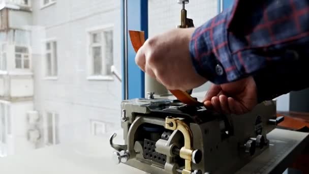 Erkek bir bronzlaştırıcı, üretim atölyesinde özel bir kareleme makinesi kullanarak bir ürünün fazla derisini yüzüyor. Cilt Kenar Kesme Makinesi — Stok video
