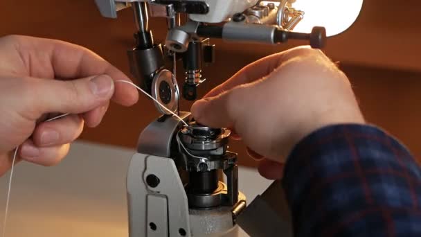 En man sätter upp en gammal symaskin för arbete. Syfabrik. — Stockvideo
