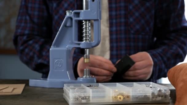 An artisan uses a press to install metal fittings. He fixes the part with the clincher in the tool and lowers the handle, pressing the button — Stock Video