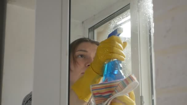Pessoas, trabalho doméstico e conceito de limpeza - mulher em luvas janela de limpeza com pano e spray de limpeza em casa — Vídeo de Stock