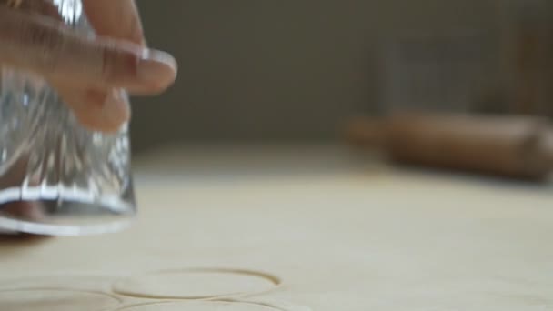 Γυναίκα κόβει κύκλους ζύμης με στρογγυλό καλούπι, ένα ποτήρι για ραβιόλια, ζυμαρικά — Αρχείο Βίντεο
