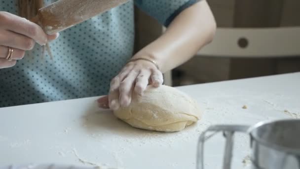 Kobieta wyrzuca forsę na stół kuchenny. Kobiece ręce toczące ciasto z wałkiem do ciasta. Pani gotuje w domu. — Wideo stockowe