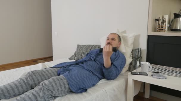 The disgusting lazy young man lies on a sofa and tries to play sports at home — Stock Video