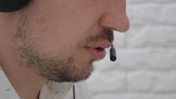 Close-up de um homem com fones de ouvido conversando em um microfone, um operador de call center trabalhando, consultando um cliente Online, um estudante estudando um idioma na Internet, ouvindo uma palestra — Vídeo de Stock