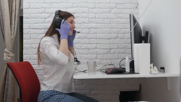 Mujer en camisa y pantalones de chándal para el hogar, pijamas con auriculares para videoconferencias, llamada para portátil en la mesa en la mesa — Vídeos de Stock