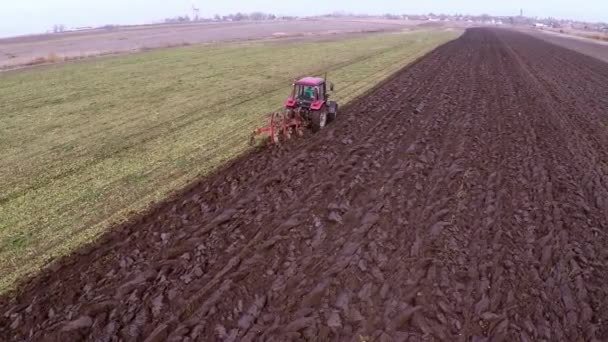 赤いトラクターの緑のフィールドで運転土地耕作機空撮 — ストック動画