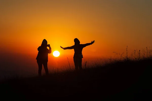 Силуэт людей, веселящихся на закате — стоковое фото