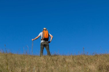 Adam mavi gökyüzü arka plan ile Hill trekking sırt çantaları ile.