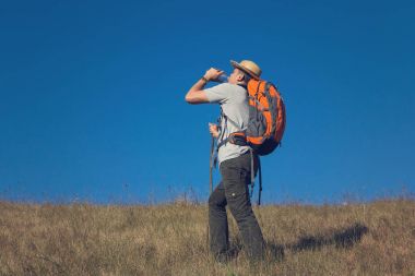 Adam mavi gökyüzü arka plan ile Hill trekking sırt çantaları ile.