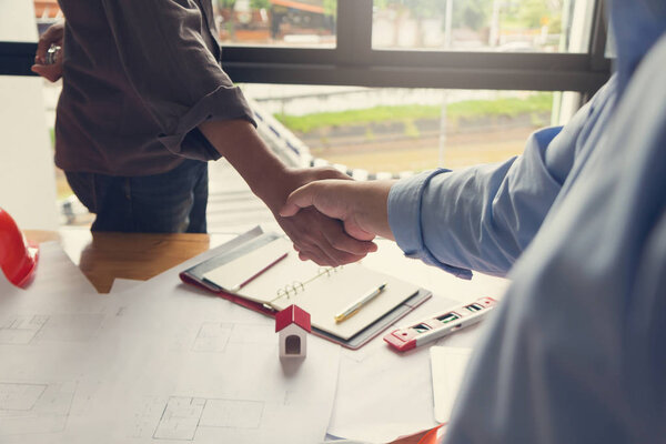 Engineer and Architect concept, Engineer Architects office team working shaking hand with blueprints and house model on office desk, Vintage Effect