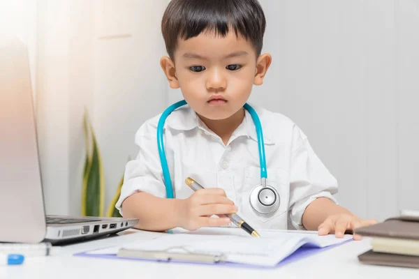 Young asian boy playing doctor and writing on diagnostic chart.