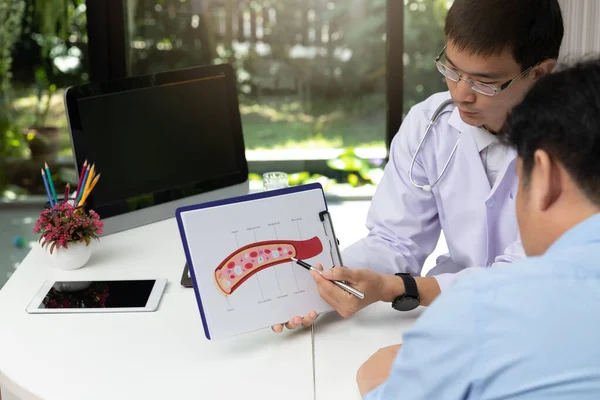 Doctor consultation Patient about  blood vessel with explain model of blood vessel on clipboard in medical office at hospital