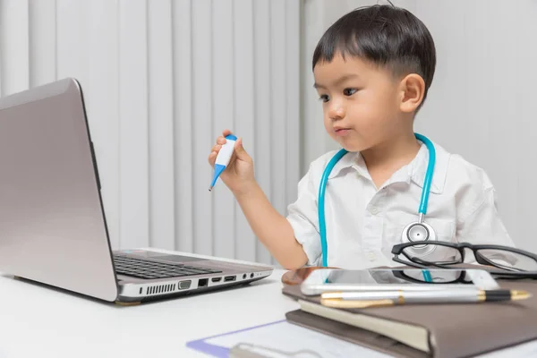 年轻的亚洲男孩玩医生和使用电脑笔记本电脑 — 图库照片