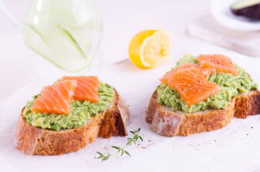 Avokado ve tuzlu somonlu iki kızarmış ekmek.