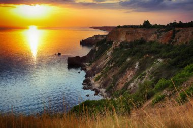 Cape Fiolent dramatik günbatımında bush ve foregroun çim ile